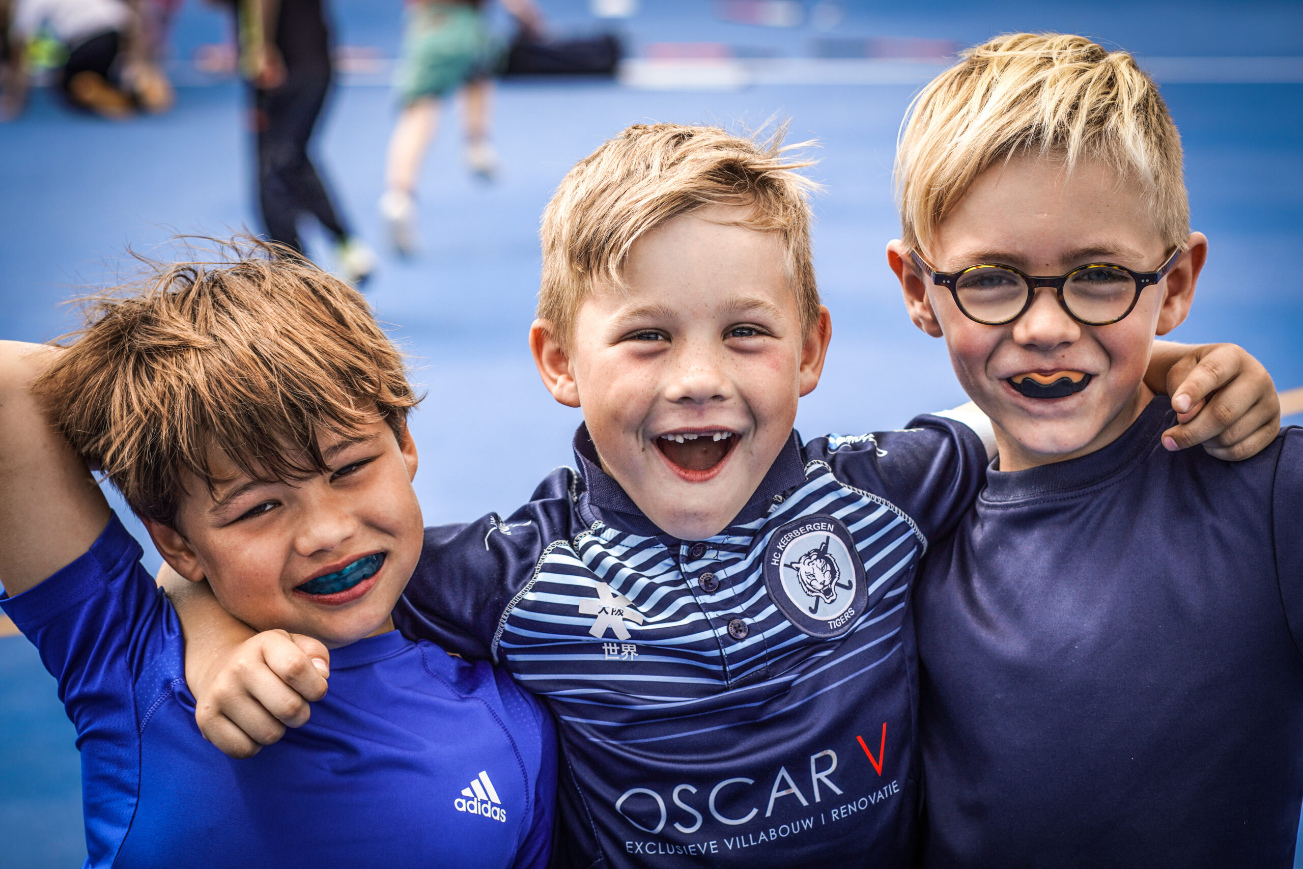 Drie jonge spelers van de Tigers lachen samen in clubshirt