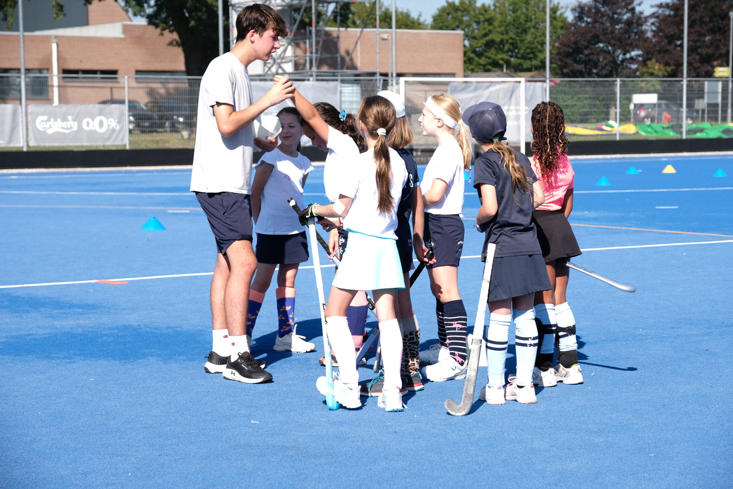 Kinderen krijgen uitleg van hun trainer tijdens een hockeystage