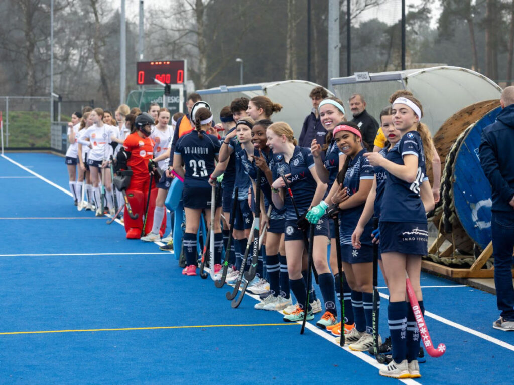 Meidenteam van de Tigers staat klaar langs het veld voor de wedstrijd
