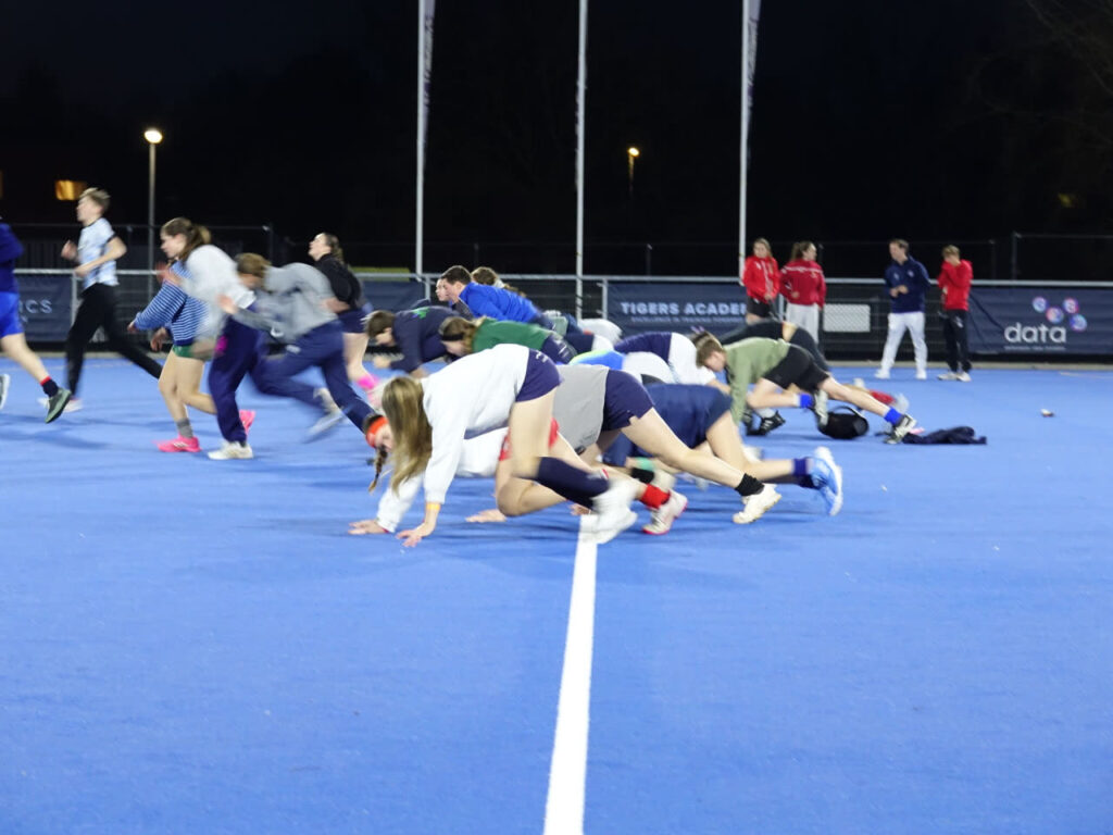Jeugdspelers doen een opwarmingsoefening op het veld