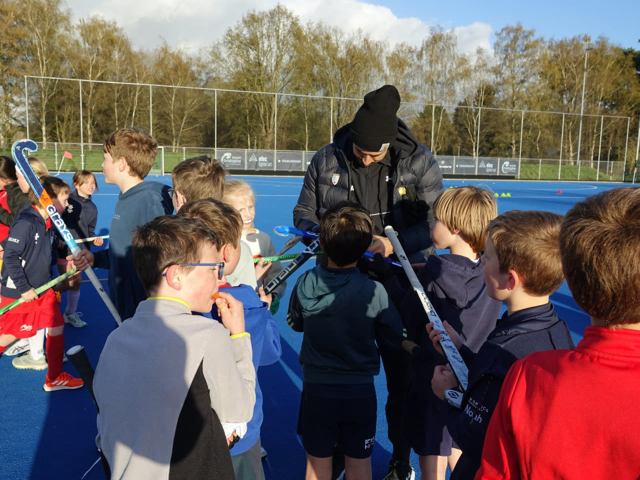 Coach legt jonge spelers iets uit langs het veld